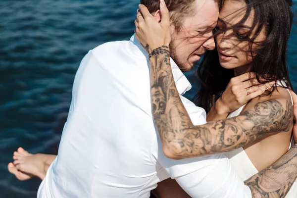 Genç çift deniz kıyısındaki iskelede oturuyor.