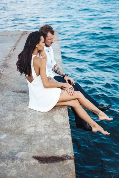 Genç çift deniz kıyısındaki iskelede oturuyor.