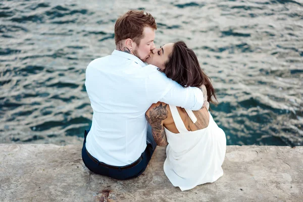 若いカップルは海の側の桟橋に座っている — ストック写真
