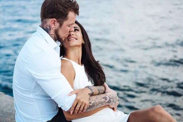 Les jeunes couples sont assis sur la jetée au bord de la mer — Photo