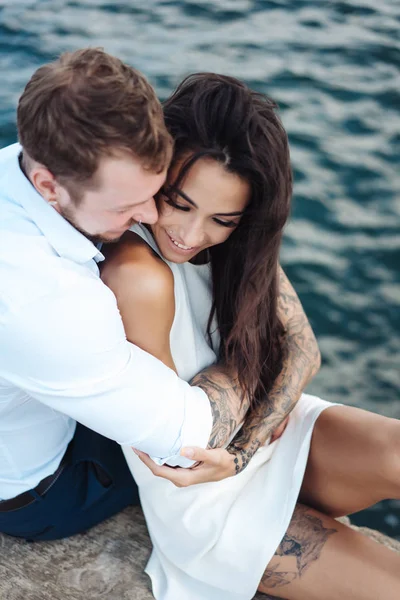 Genç çift deniz kıyısındaki iskelede oturuyor.