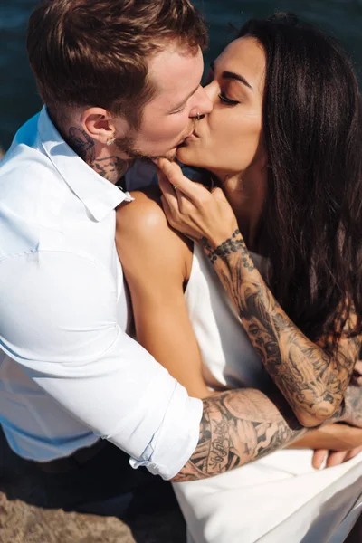 Genç çift deniz kıyısındaki iskelede oturuyor.