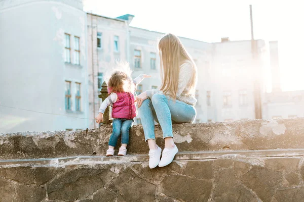 Anne ve kızı çitte birlikte oturuyorlar.