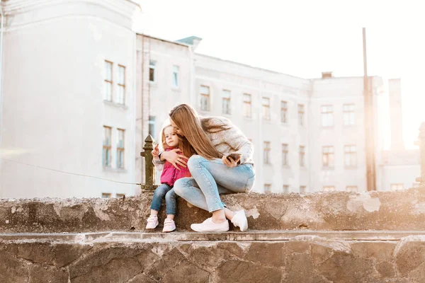 Mama i córka siedzą razem na ogrodzeniu — Zdjęcie stockowe