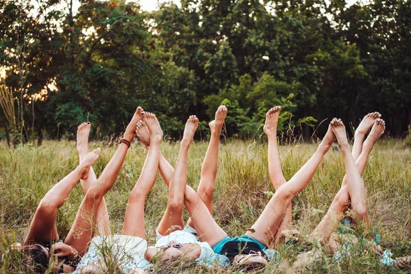 Шесть девушек лежат на траве и поднимают ноги — стоковое фото