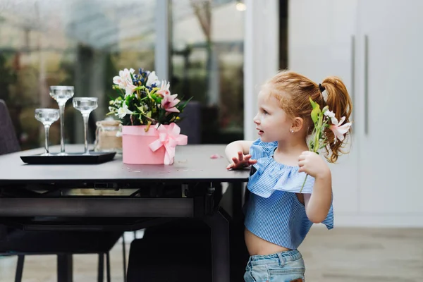 Liten flicka sätter blommor på bordet — Stockfoto