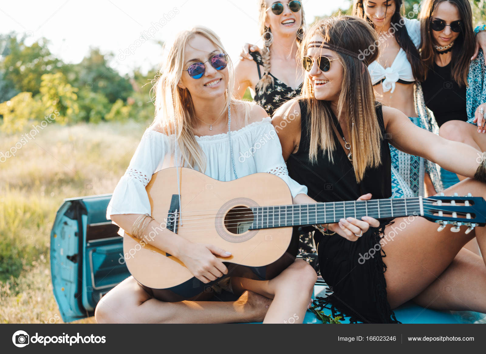 girls are sitting on the trunk with a guitar stock photo