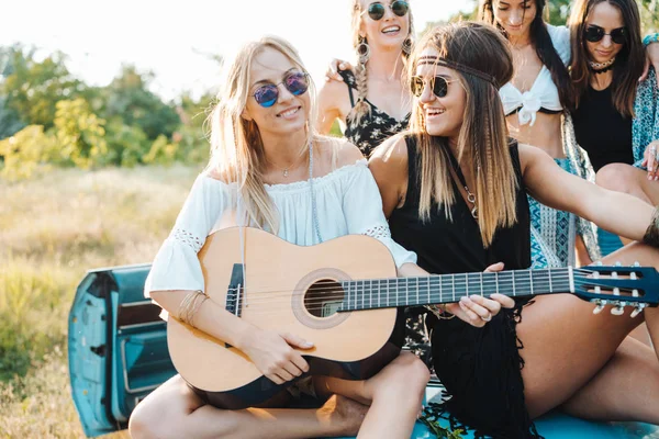 Tjejer sitter på stammen med en gitarr — Stockfoto