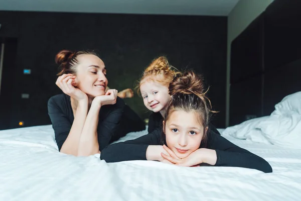 Mamma och två döttrar har kul på sängen — Stockfoto