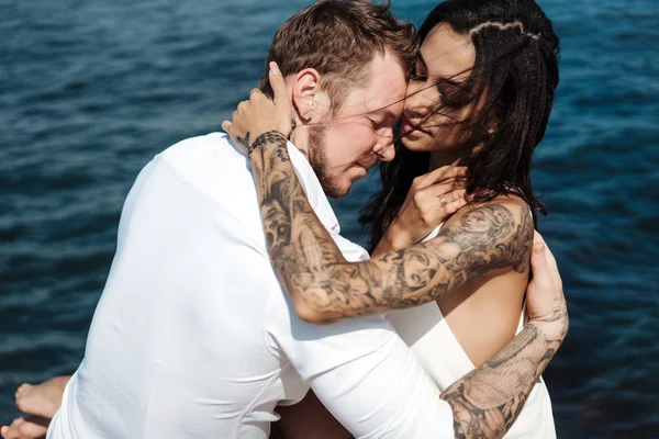 Genç çift deniz kıyısındaki iskelede oturuyor.