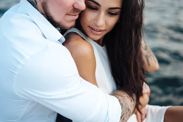 Casal jovem está sentado no cais junto ao mar — Fotografia de Stock