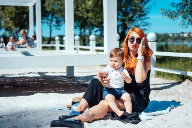 Anne ve oğlu göl kenarındaki kumsalda dinleniyor.