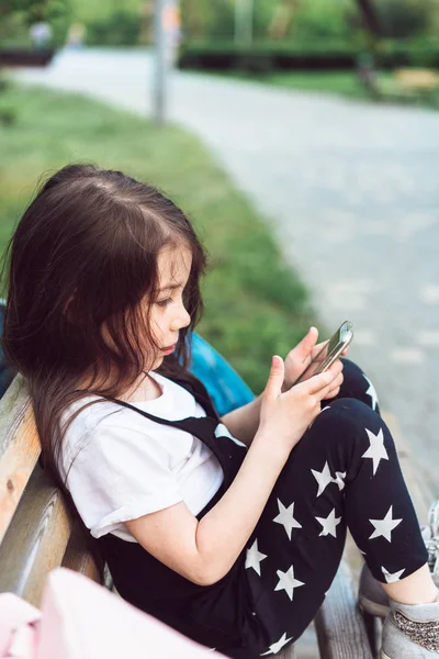 벤치에 앉아 스마트폰으로 어린 소녀 — 스톡 사진