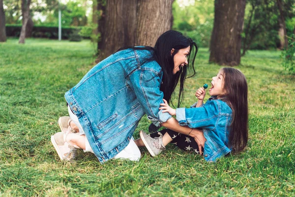 Mamá y su hija en el césped se divierten — Foto de Stock