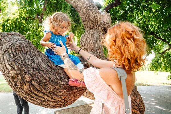 Little girl is sitting on a branch — Stock Photo, Image