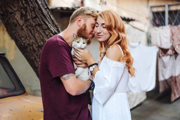 Dışarıda poz veren güzel bir çift ve kedi.