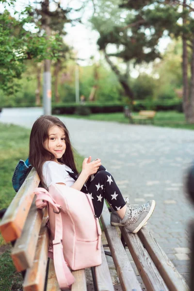 Маленькая девочка со смартфоном сидит на скамейке — стоковое фото