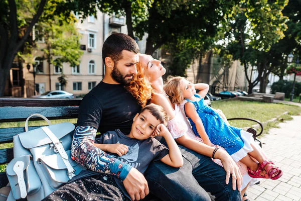 Красивая молодая семья отдыхает на скамейке — стоковое фото