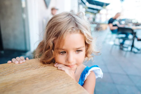 Little girl in a blue dress near a small table