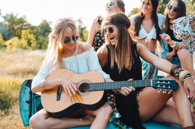Kızlar gövdede bir gitarla oturuyorsun