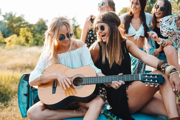Κορίτσια κάθονται στον κορμό με μια κιθάρα — Φωτογραφία Αρχείου