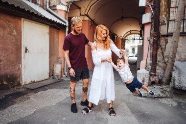 Mutlu ebeveynler dışarıda oğluyla oynuyorlar.