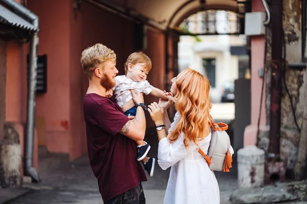 Mutlu ebeveynler dışarıda oğluyla oynuyorlar.