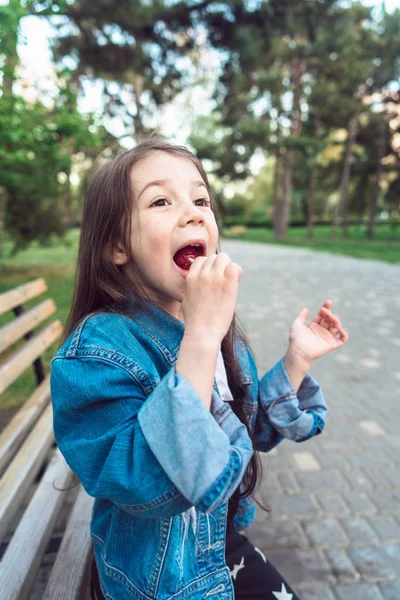 Menina sentada no banco com doces — Fotografia de Stock