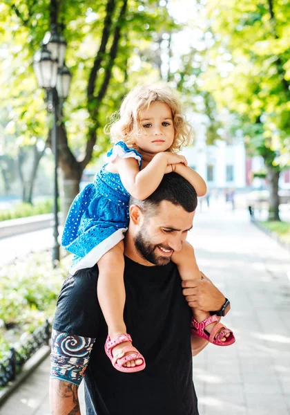 Маленькая девочка едет на шее отцов — стоковое фото