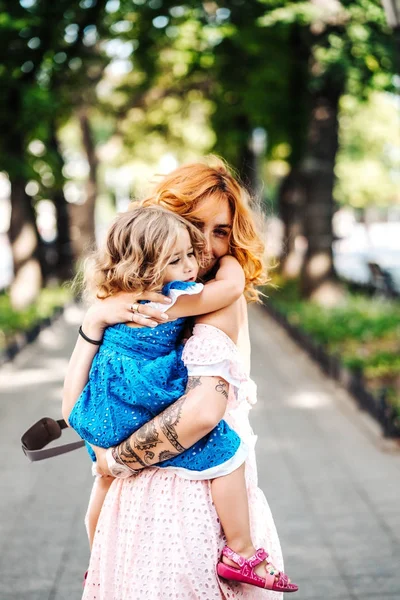 Mulher abraça sua filha, segurando-a em seus braços — Fotografia de Stock