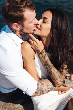 Genç çift deniz kıyısındaki iskelede oturuyor.