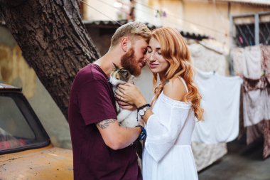 Dışarıda poz veren güzel bir çift ve kedi.