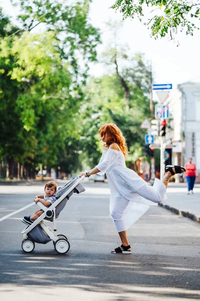 Мама с коляской переходит дорогу — стоковое фото