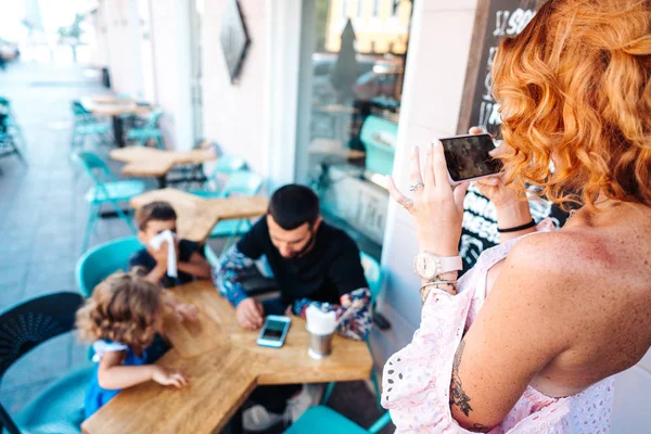 Família em um café, mamãe tira uma foto — Fotografia de Stock