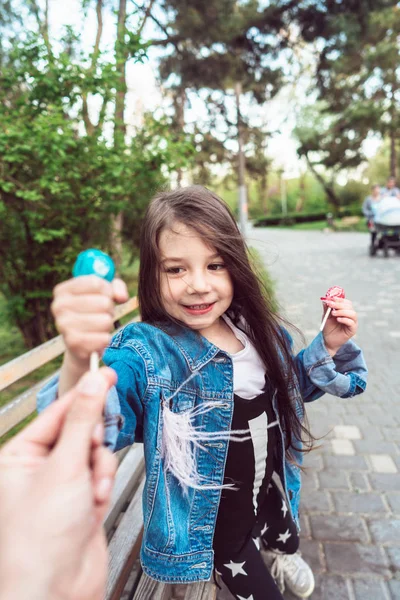 Dívka sedící na lavičce s bonbóny — Stock fotografie