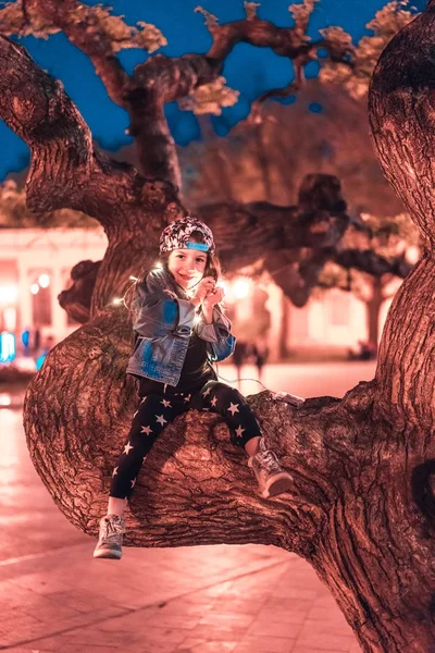 Niña preescolar sentada en una rama de árbol — Foto de Stock