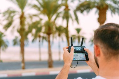 Adam uzaktan kumandayla dronu kontrol ediyor.