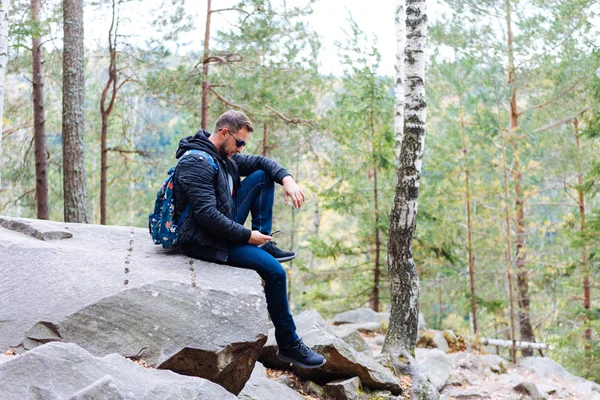 Ο τύπος που κάθεται στο δάσος σε ένα βράχο — Φωτογραφία Αρχείου