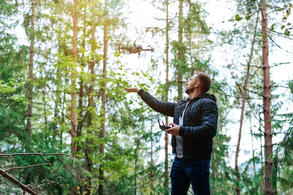 Mec commence un quadrocopter dans la forêt — Photo