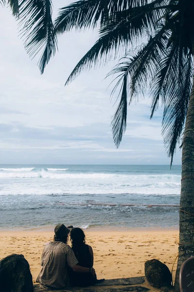 Casal sentado sob palmeiras — Fotografia de Stock