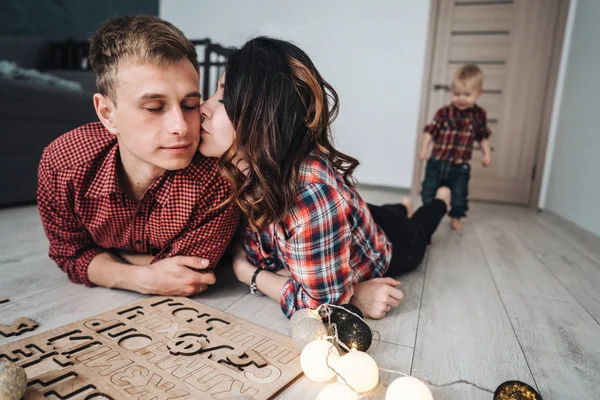 Mamma kysser pappa på golvet i barnkammaren — Stockfoto