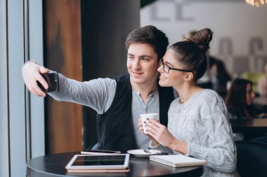 Bir adam ve bir kız birlikte bir kafede oturuyor.