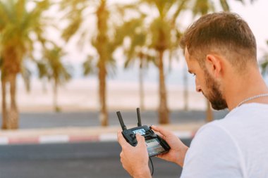 Adam uzaktan kumandayla dronu kontrol ediyor.