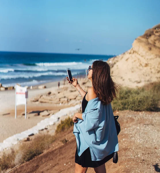 Молодая женщина делает фото на смартфоне — стоковое фото