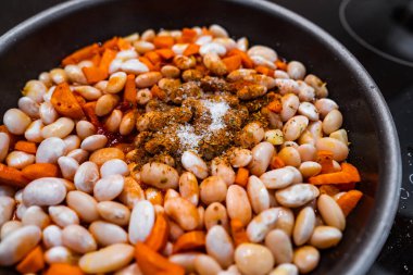 Pişirmeden önce havuç, sarımsak ve tuzlu fasulye ve baharatlı tava..
