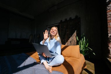 Gülümseyen çekici kadın yatakta laptop kullanarak yatıyor
