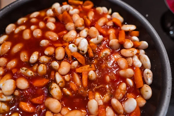 Wortelen, knoflook en bonen met tomatensaus in een pan voor het koken. Sluiten sluier — Stockfoto