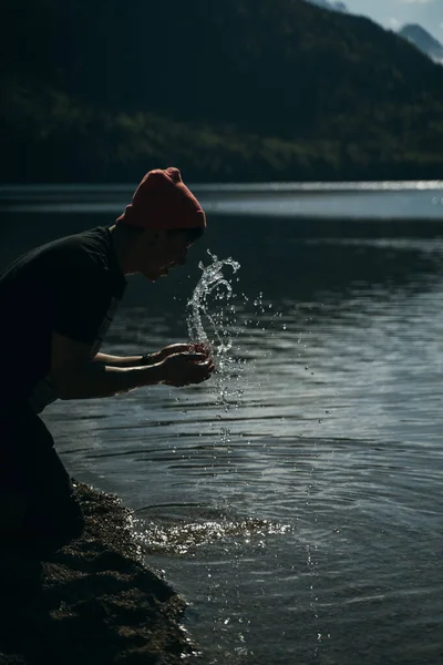 Ένας άντρας πλένει τα χέρια του στην όχθη μιας λίμνης δάσους. — Φωτογραφία Αρχείου