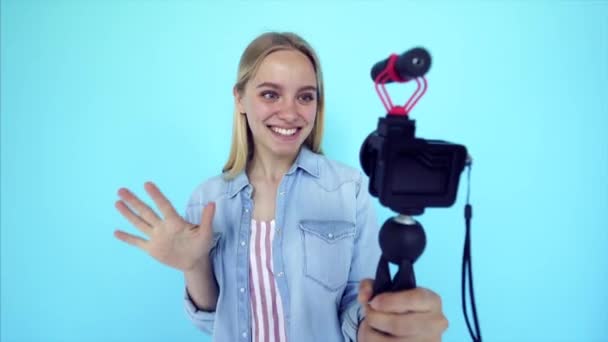 Bella ragazza blogger si solleva a macchina fotografica isolato sfondo blu — Video Stock