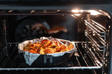Baked potatoes with carrot and other spices in roasting pan. clipart